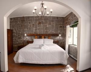 a bedroom with a white bed with a stone wall at Casa de Pedra Mena Kaho in Bento Gonçalves
