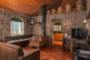 a living room with stone walls and a tv and a couch at Casa de Pedra Mena Kaho in Bento Gonçalves