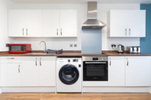 a kitchen with a washing machine and a microwave at 1BR Hideaway in Coventry - MH Apartment in Coventry