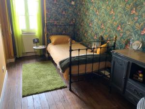 1 dormitorio con 1 cama con papel pintado verde en Welcoming and peaceful bed and breakfast, en Fougerolles-du-Plessis