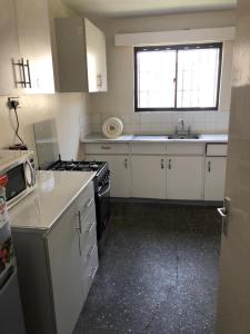 uma cozinha com armários brancos, um lavatório e um fogão em Homes by Val em Nairobi