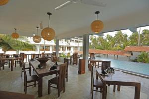 ein Restaurant mit Holztischen und -stühlen und einem Pool in der Unterkunft The Beach Boutique in Uswetakeiyawa