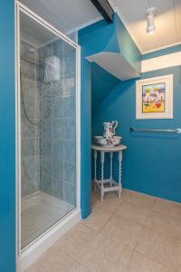 a blue bathroom with a shower and a table at The Old Farmhouse in Liskeard