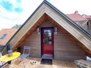 una casa con puerta roja, mesa y sillas en La forge de Godincthun en Pernes-lès-Boulogne