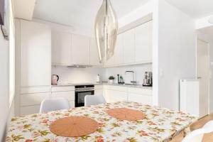 Biała kuchnia ze stołem i białymi szafkami w obiekcie Bergen's Finest: Sleek Oasis with Two Bedroom w Bergen