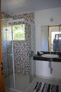 y baño con ducha acristalada y lavamanos. en Suítes Paquetá Ilhabela, en Ilhabela