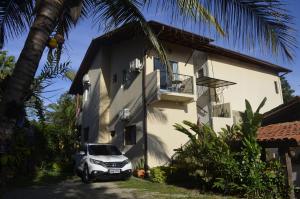 une voiture blanche garée devant un bâtiment dans l'établissement Suítes Paquetá Ilhabela, à Ilhabela