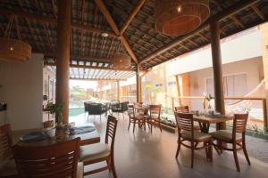 a restaurant with wooden tables and chairs and a patio at Uri Pousada in Maragogi