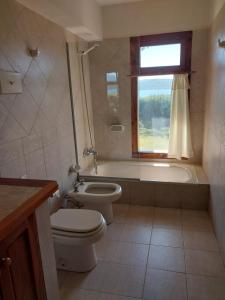 a bathroom with a toilet and a tub and a window at Casa con costa del lago in Dina Huapi