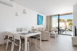 a white kitchen and living room with a white table and chairs at Mirador Blue K Cala Sant Vicenc in Cala de Sant Vicenc