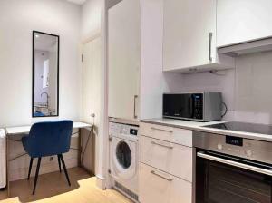 a kitchen with a washing machine and a blue chair at Mayfair Stylish central London Modern Suite in London