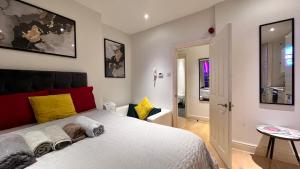 Schlafzimmer mit einem Bett mit rotem Kopfteil und gelben Kissen in der Unterkunft Mayfair Stylish central London Modern Suite in London