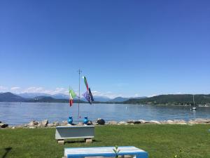a bench with three flags on it next to a body of water at Bnbook Lago Maggiore Studio in Castelletto sopra Ticino