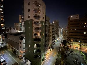 ein hohes Gebäude in einer Stadt in der Nacht in der Unterkunft CowCow Hotel Shinjuku in Tokio