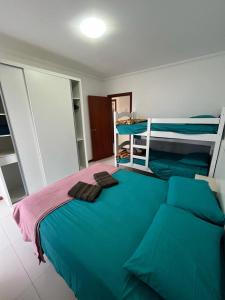 um quarto com uma cama com lençóis azuis e beliches em Residencial Maria Elena em Florianópolis