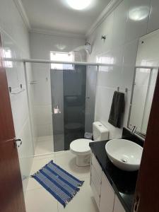 Baño blanco con aseo y lavamanos en Residencial Maria Elena, en Florianópolis