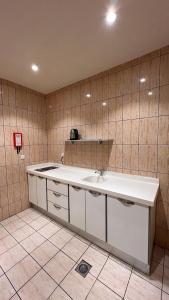 La salle de bains est pourvue d'un lavabo blanc et d'un mur carrelé. dans l'établissement رواح للشقق المخدومة- الحوية, à Al Muraysīyah