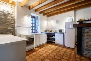 a large kitchen with white appliances and wooden ceilings at The Coach House - Avec piscine partagée in Osserain-Rivareyte