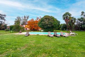 a group of benches sitting in the grass near a pool at The Coach House - Avec piscine partagée in Osserain-Rivareyte