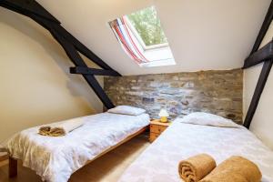 two beds in a attic bedroom with a window at The Coach House - Avec piscine partagée in Osserain-Rivareyte