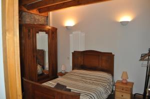 a bedroom with a wooden bed and a mirror at The Coach House - Avec piscine partagée in Osserain-Rivareyte