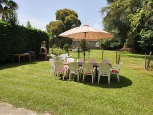 a table and chairs under an umbrella in the grass at The Coach House - Avec piscine partagée in Osserain-Rivareyte