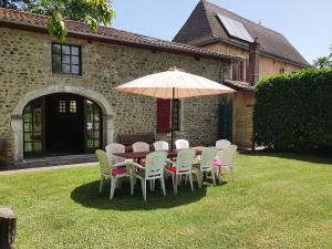 a table and chairs with an umbrella in a yard at The Coach House - Avec piscine partagée in Osserain-Rivareyte
