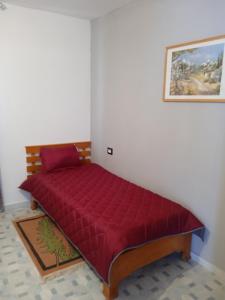 Cama en habitación con colcha roja en l'olivier en Aghīr