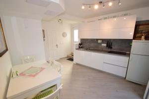 a kitchen with white cabinets and a table and a counter at Apartment &Scaron;ulić in Dubrovnik
