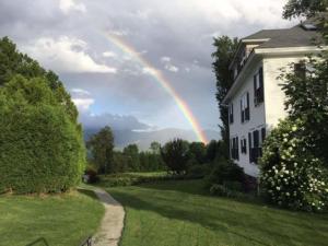 um arco-íris no céu sobre uma casa em Sunset Hill House em Sugar Hill