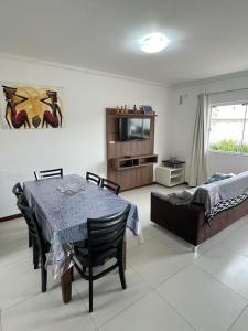 uma sala de estar com uma mesa, uma cama e uma televisão em Residencial Maria Elena em Florianópolis