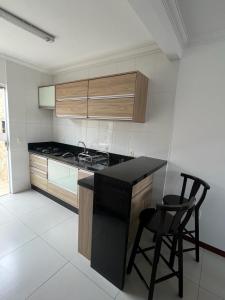 uma cozinha com um balcão preto e duas cadeiras em Residencial Maria Elena em Florianópolis