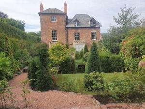 an old brick house with a garden in front of it at Clairville : Georgian Suite - Central Ross-on-Wye in Ross on Wye