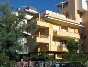 un bâtiment jaune avec des balcons sur son côté dans l'établissement Family comfort in Bibione - Beahost, à Bibione