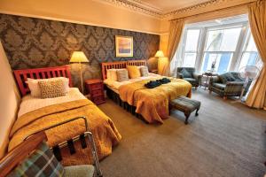 a hotel room with two beds and a chair at Burnside Guest House in Ayr