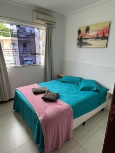 1 dormitorio con cama con sábanas azules y ventana en Residencial Maria Elena, en Florianópolis