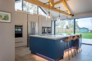 una cocina con una isla azul con taburetes de bar en West Heath 10, en Brancaster