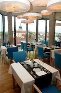 un restaurant avec des tables, des chaises bleues et des fenêtres dans l'établissement Hotel Erwin Junker, à Holice