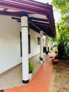 Breeze Blows- Solitude Holiday Home في ماتارا: فناء مع مظلة والنباتات على مبنى