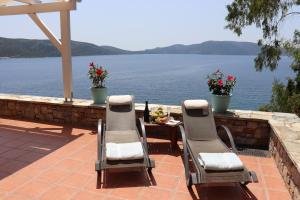 a patio with chairs and a table with a view of the water at Alonissos Luxury Villa with Jacuzzi and Beach in Agios Dimitrios