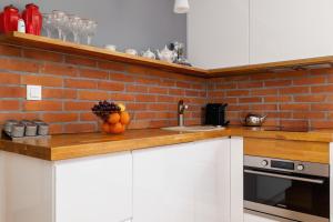 a kitchen with white cabinets and a brick wall at Comfortable Apartment Chramcówki in the Centre of Zakopane by Renters in Zakopane