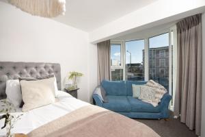 a bedroom with a bed and a blue chair at Bathsheba, Ocean 1 in Newquay