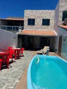 einen Pool mit roten Stühlen und Tischen und ein Haus in der Unterkunft Casa Arembepe 2 in Camaçari