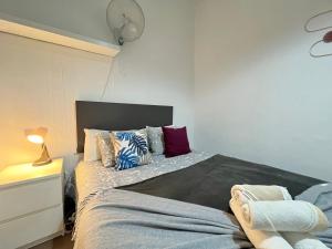 1 dormitorio con cama con almohadas y reloj en la pared en Ile Aina Exterior Nuevo Peña, en Madrid