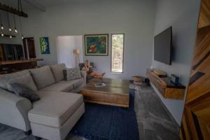 a woman sitting in a living room with a couch at Modern Villa Overlooking Macal River Valley in Benque Viejo del Carmen