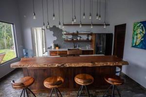 a kitchen with a bar with four stools at Modern Villa Overlooking Macal River Valley in Benque Viejo del Carmen