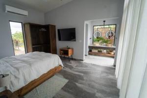 ein Schlafzimmer mit einem Bett und einem TV in der Unterkunft Modern Villa Overlooking Macal River Valley in Benque Viejo del Carmen