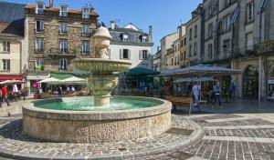 a fountain in the middle of a street with buildings at Maison de ville entre Disneyland et Paris. in Lagny