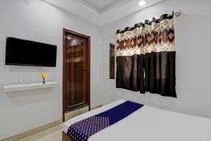 1 dormitorio con 1 cama y TV en la pared en OYO Zois Nest, en Kammasandra