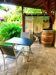 una mesa con sillas y un barril en el patio en Kaz Alberto Guadeloupe, en Sainte-Rose